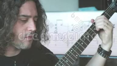 长头发的摇滚作曲家音乐家男子带耳机演奏电吉他与音乐配乐屏幕背景